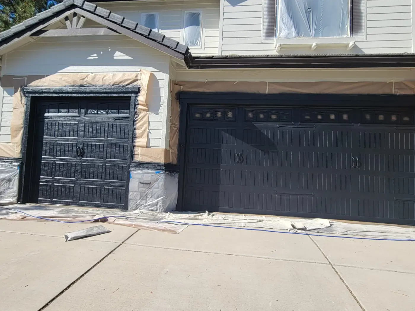 Garage doors painted black against cream stucco on a two-story Reno, NV home