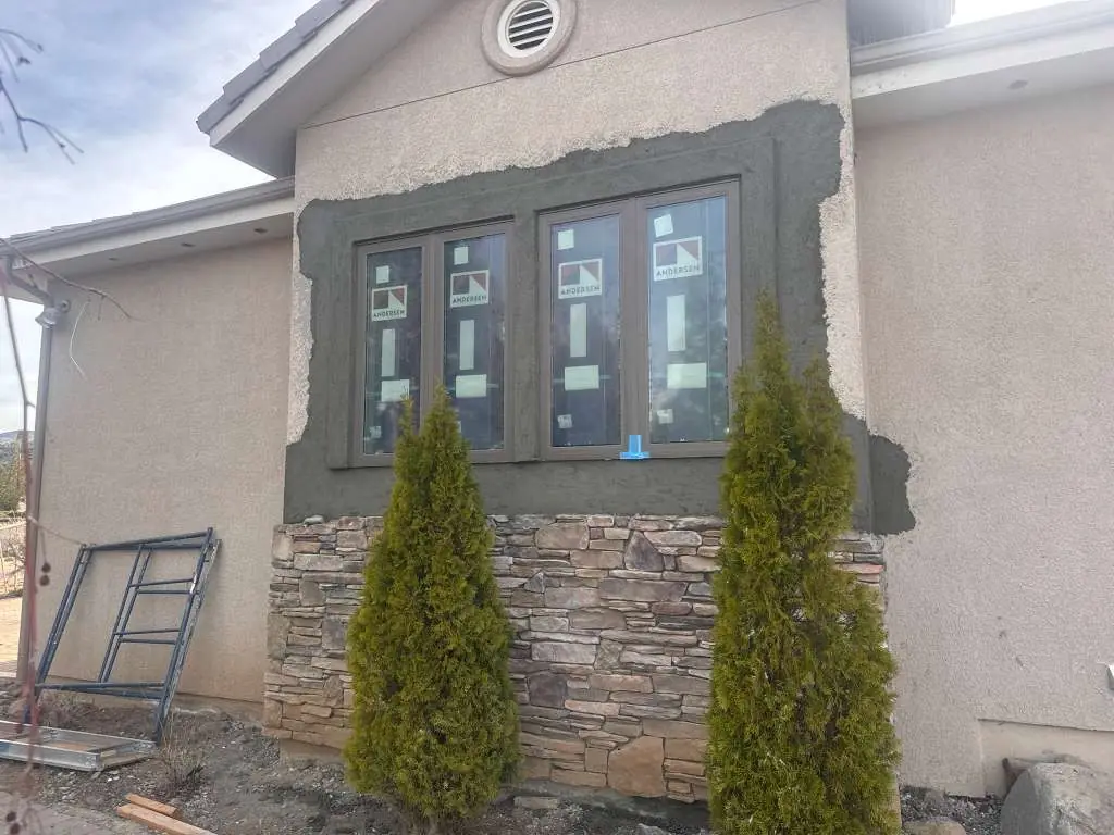 Stucco base coat applied around new Andersen windows above stone veneer in Reno, NV