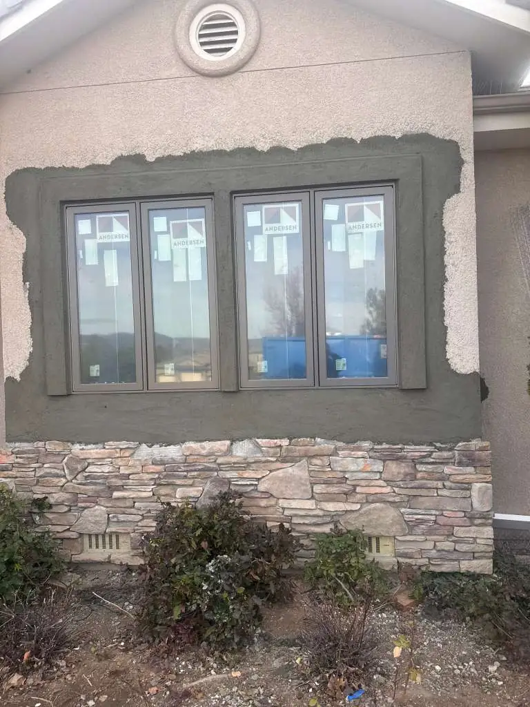 Stucco brown coat applied around new Andersen windows above stone veneer in Reno, NV