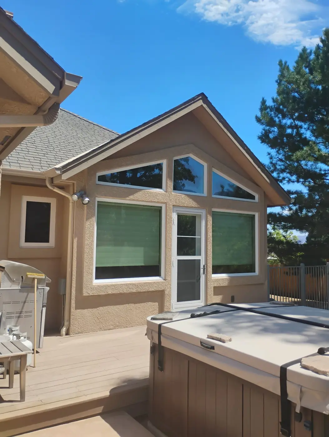 Tan stucco home exterior with gable windows, deck and hot tub on a sunny day in Reno, NV