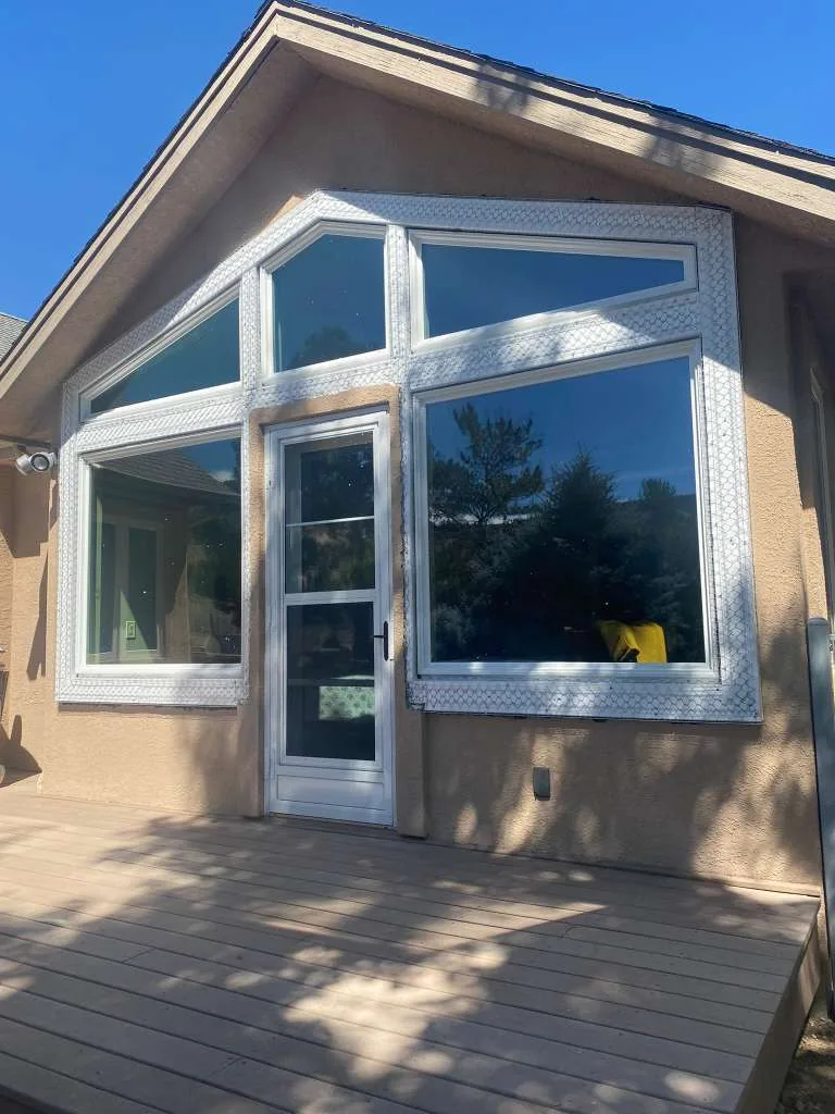 Tan stucco home with large picture windows and wood deck under blue sky in Reno, NV