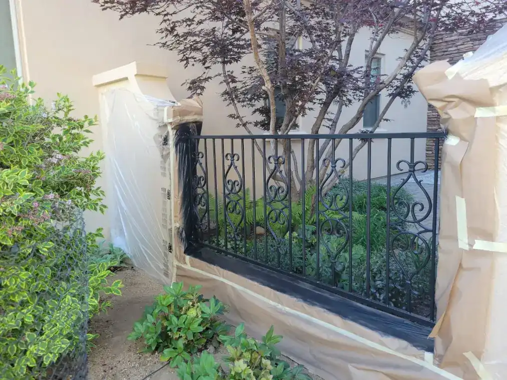 Freshly recoated tan stucco garden wall with black iron fence in Reno, NV